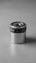 A perfectly centered Land Rover oil filter on a clean, textured surface in Graphite Gray. The product is captured with...